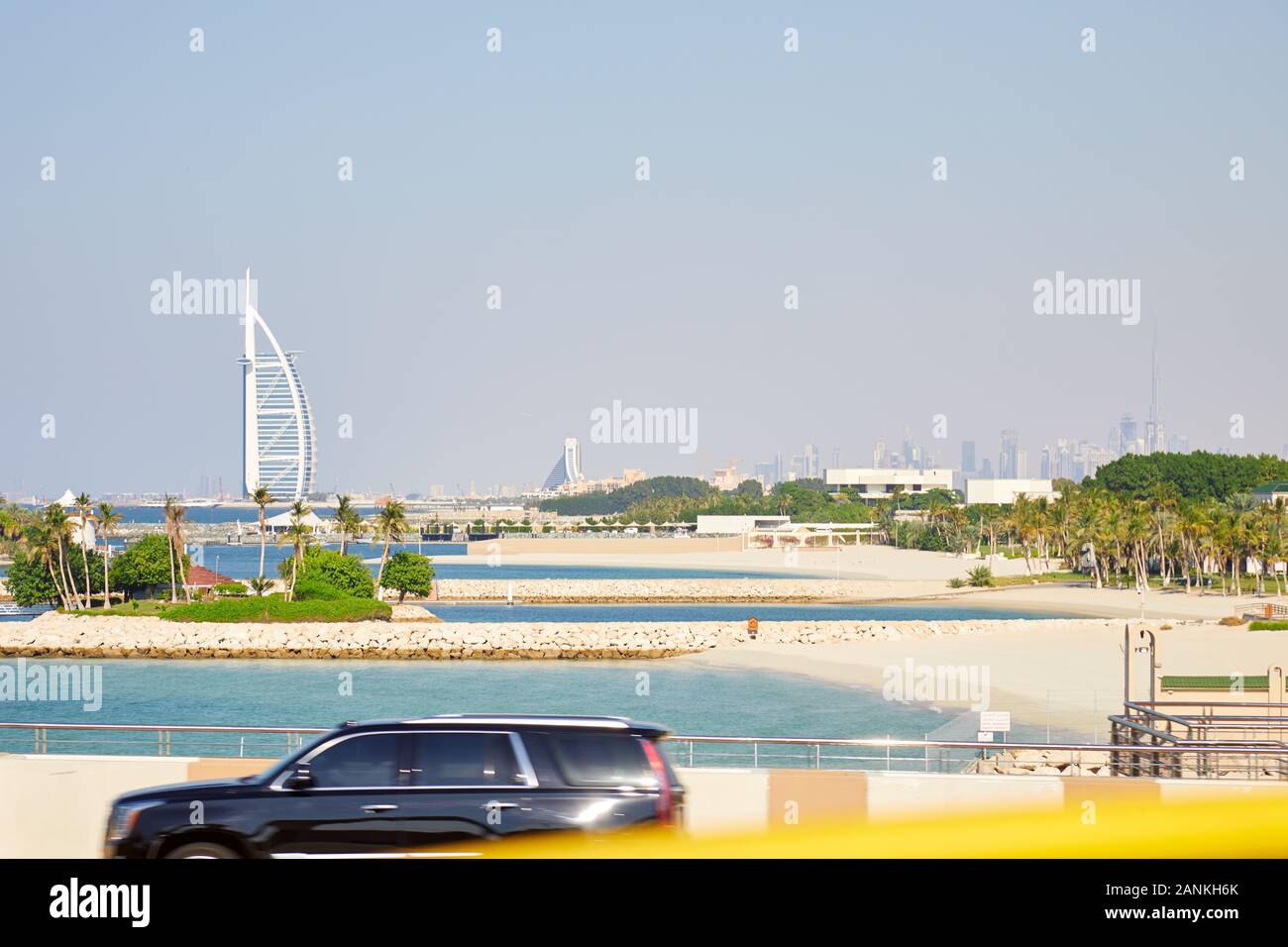 DUBAI, VEREINIGTE ARABISCHE EMIRATE - November 23, 2019: Burj Al Arab, Luxushotel mit Palmen und Dubai Skyline der Stadt an einem sonnigen Tag Stockfoto