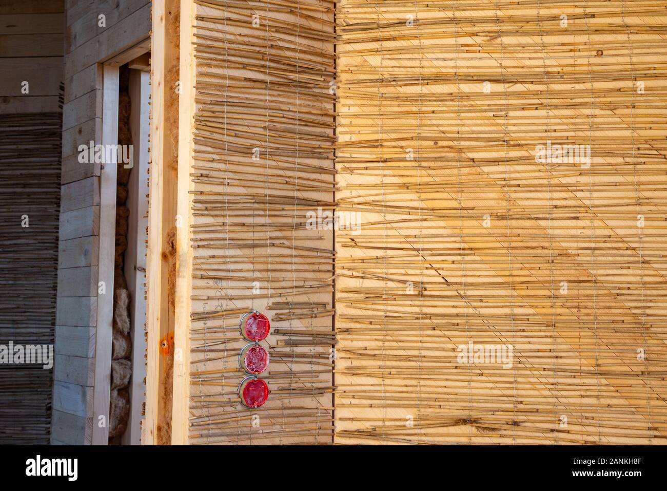 Feste reed Mats auf einer Holzwand für plastring die Wände mit Lehm und Sand - Begriff der Moderne und ökologische Architektur vorbereitet Stockfoto