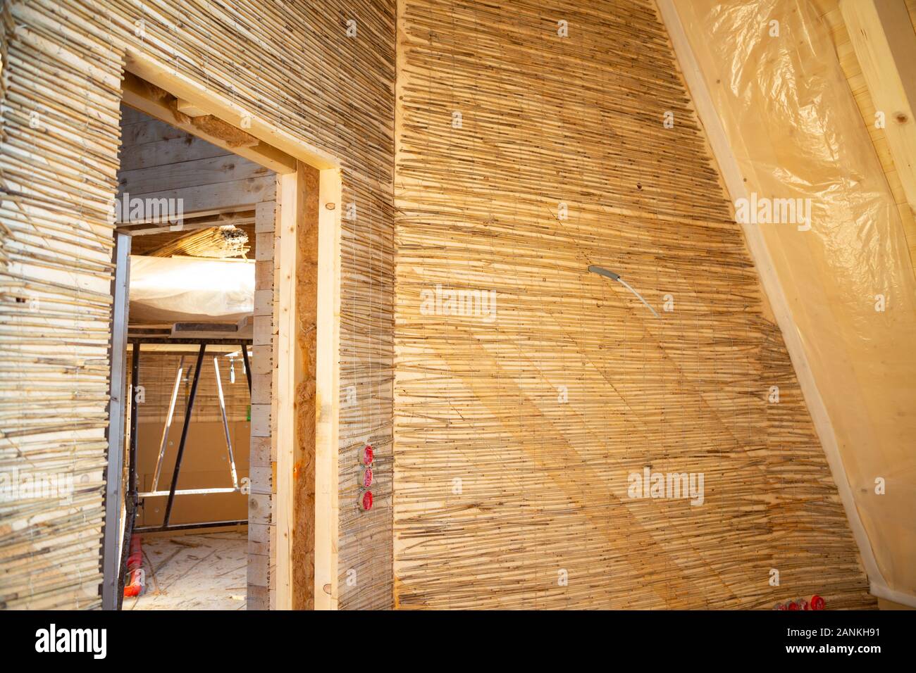 Feste reed Mats auf einer Holzwand für plastring die Wände mit Lehm und Sand - Begriff der Moderne und ökologische Architektur vorbereitet Stockfoto