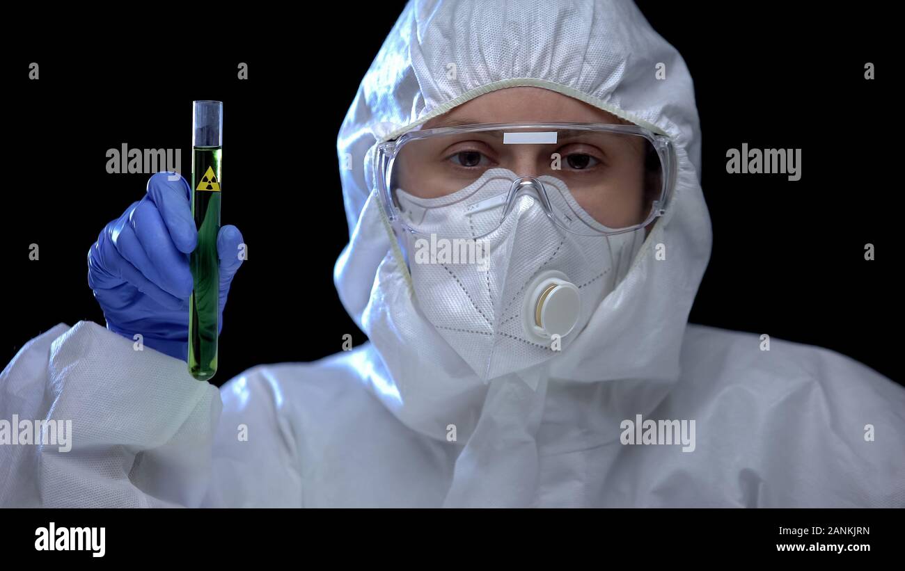 Frau in Schutzanzug Prüfung der grünen Flüssigkeit ionisierender Strahlung, illegale Lab Stockfoto