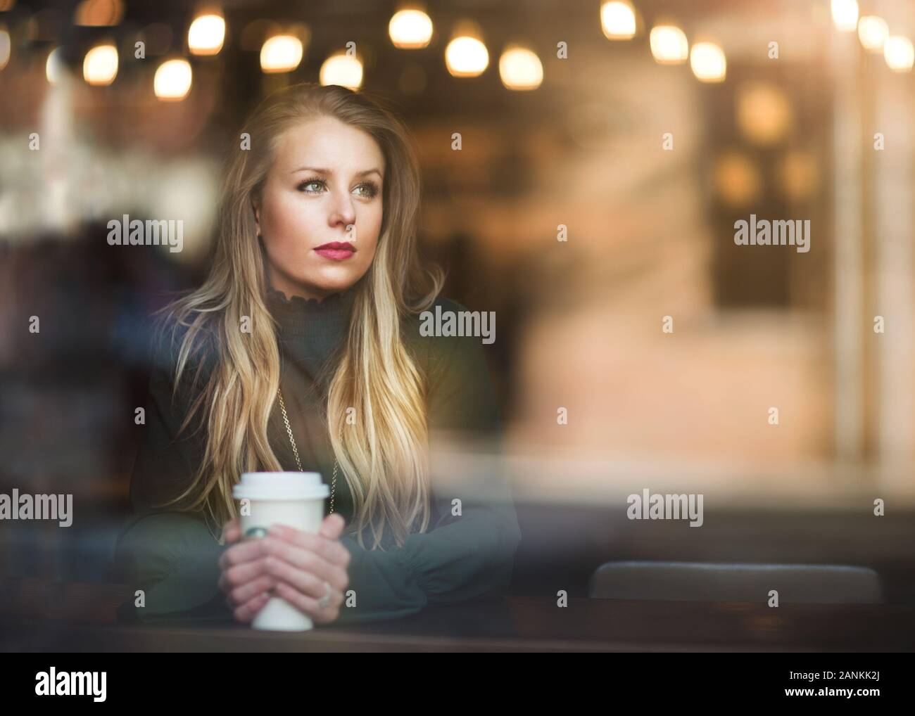 Eine junge und schöne Frau, die ihren Kaffee in einem Café genießt Stockfoto