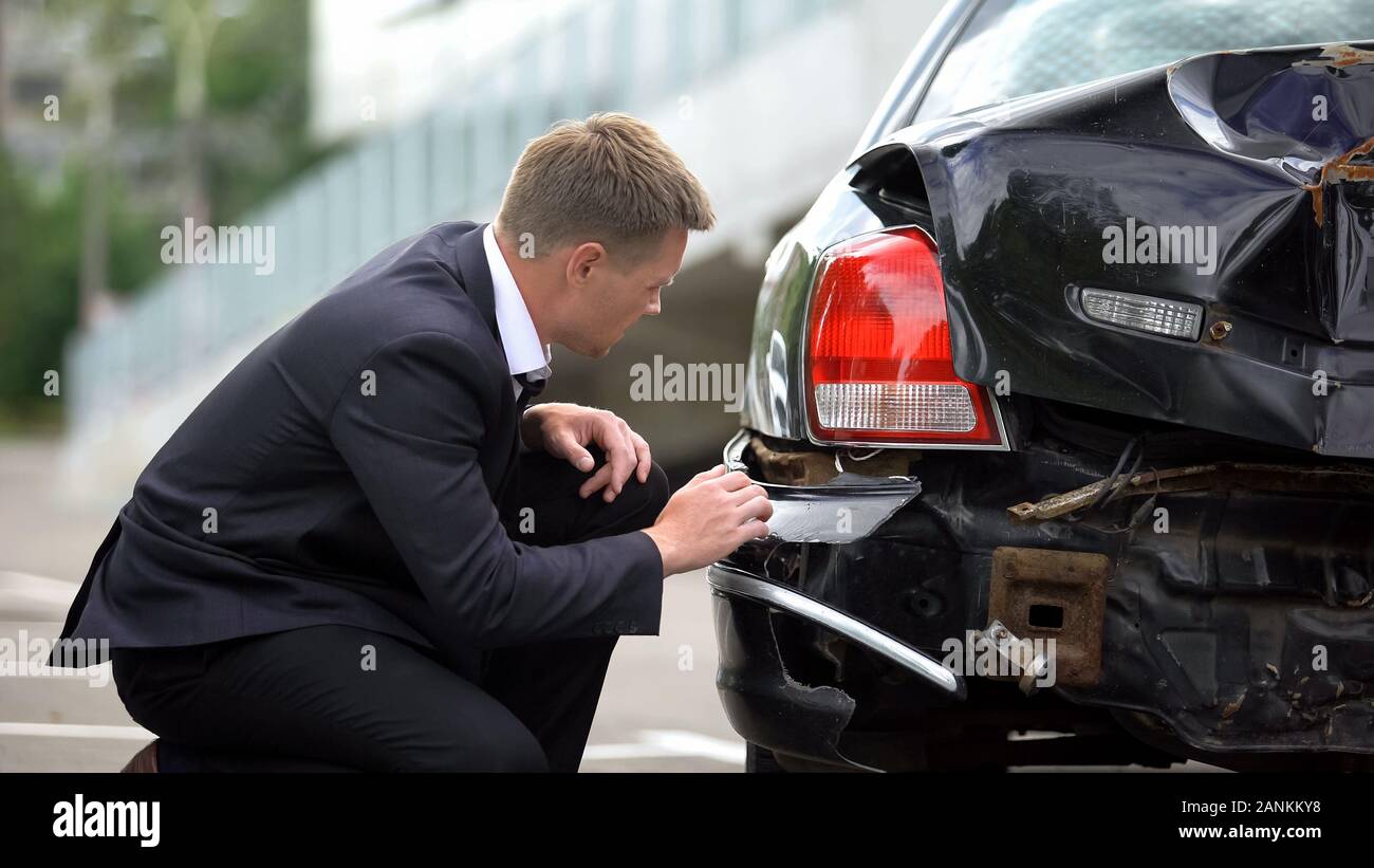 Kaukasische Mann auf der Suche nach Abgestürzte Auto Auto Unfall, Schäden, Reparatur, Versicherung Stockfoto