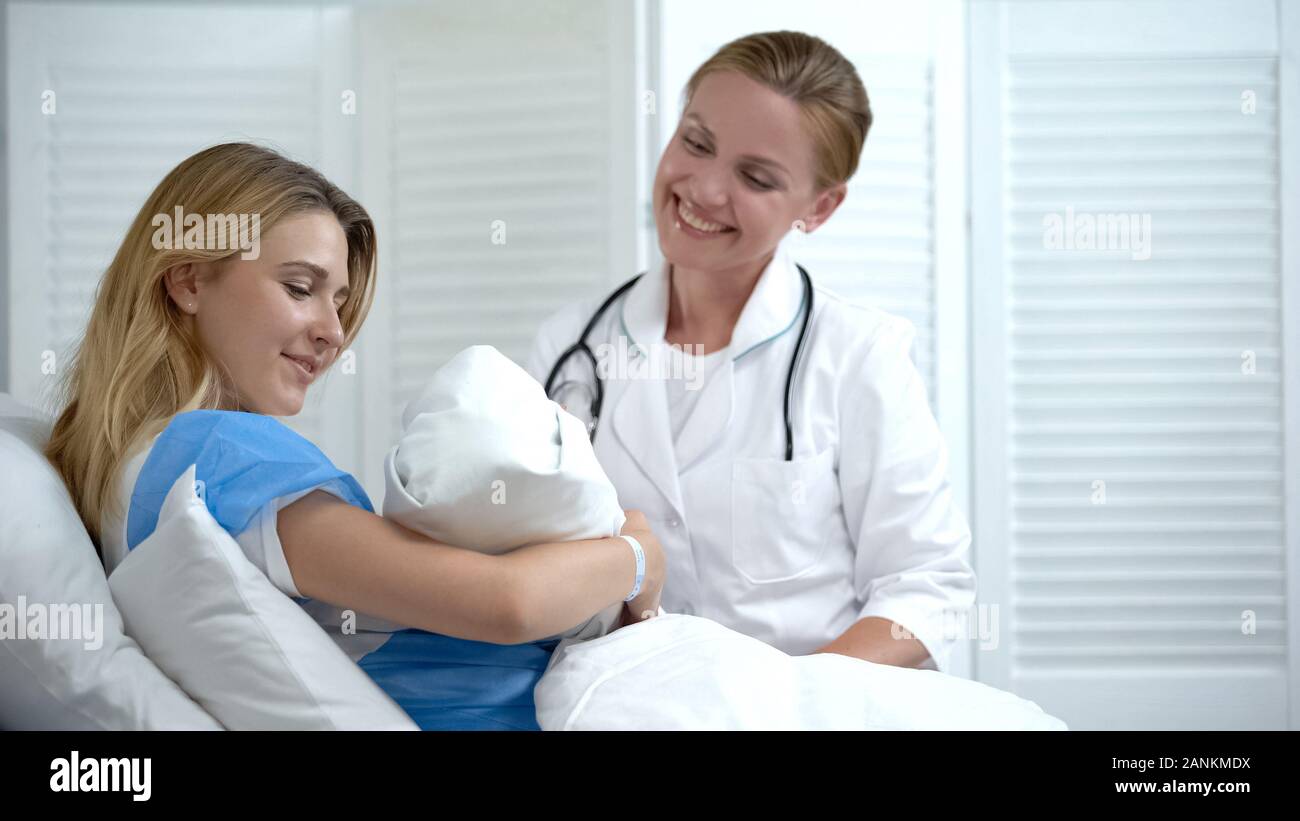 Happy Mother holding newborn baby, lächelnd Arzt am Kind suchen, Mutterschaft Stockfoto