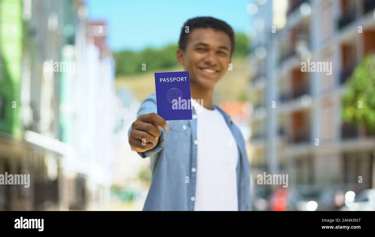 Fröhlich gemischt, Rennen, jugendlich Kerl mit internationalen Reisepass und lächelnd, Reisen Stockfoto