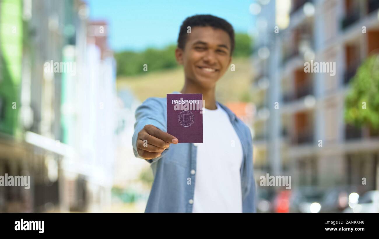 Freudige afro-amerikanischer Mann jugendlich mit Reisepass und lächelnd auf Cam, Staatsbürgerschaft Stockfoto
