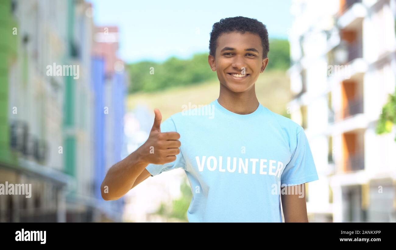 Frohe afro-amerikanischer jugendlicher Freiwilliger angezeigt Thumbs-up und lächelnd vor der Kamera Stockfoto