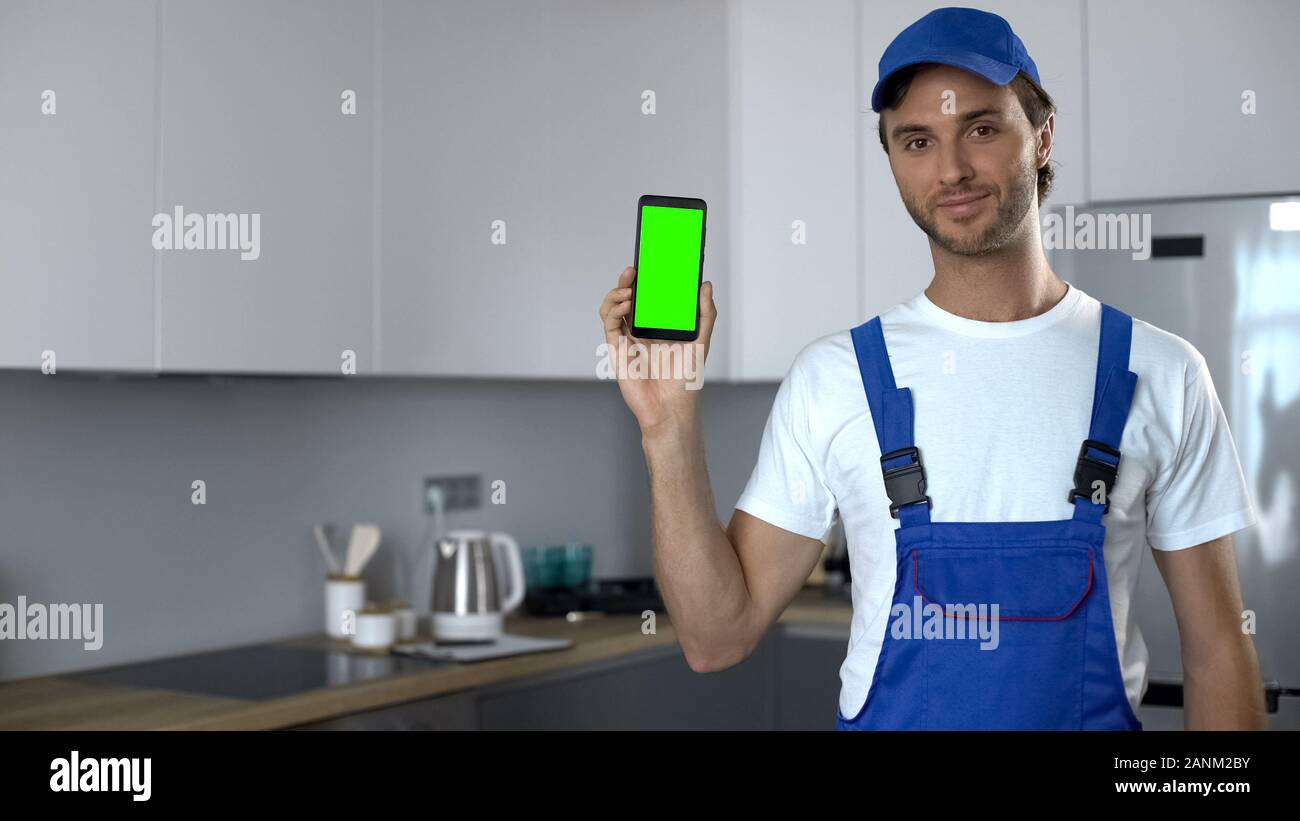 Mann in Uniform zeigen, Telefon mit Green Screen, Buchung von Haus Reparatur Service Stockfoto