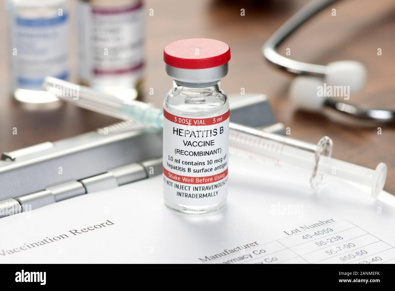 Hepatitis B-Impfstoffs auf der Arzt Schreibtisch mit Impfpass, Spritze und Stethoskop. Stockfoto