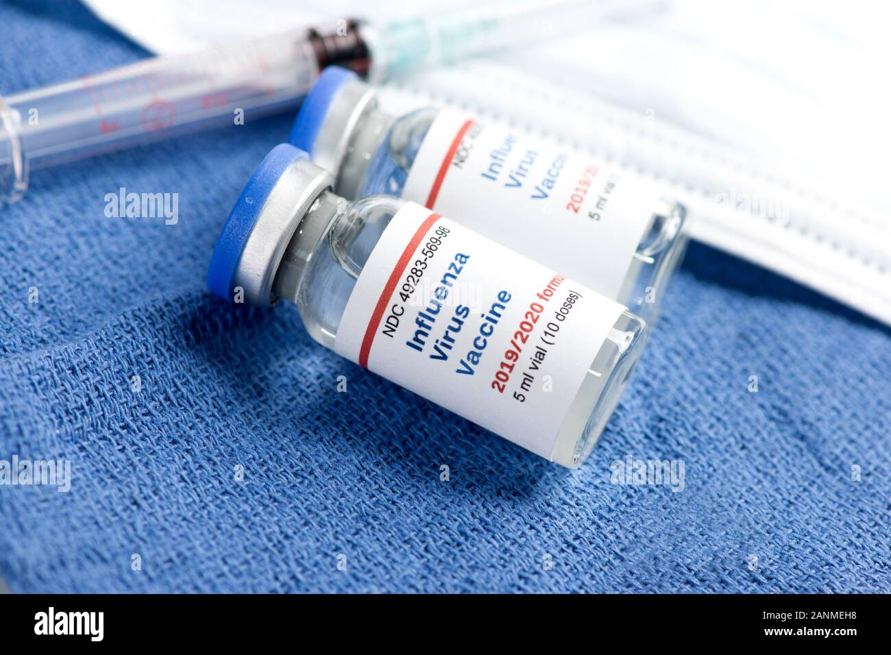 Zwei 2019-2020 Influenza Virus Impfstoff Durchstechflaschen mit Spritze auf sterilen Tuch mit Maske und Handschuhe. Stockfoto