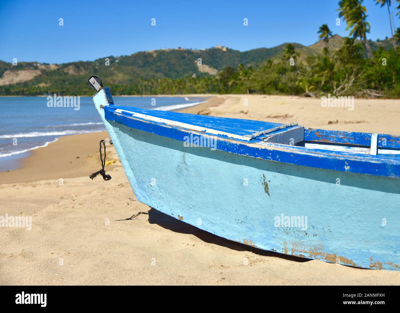 Nahaufnahme eines traditionellen Puerto Rican Fischerboot auf einen Sandstrand mit Palmen und grünen Hügeln im Hintergrund. Kopieren Sie Platz. Stockfoto