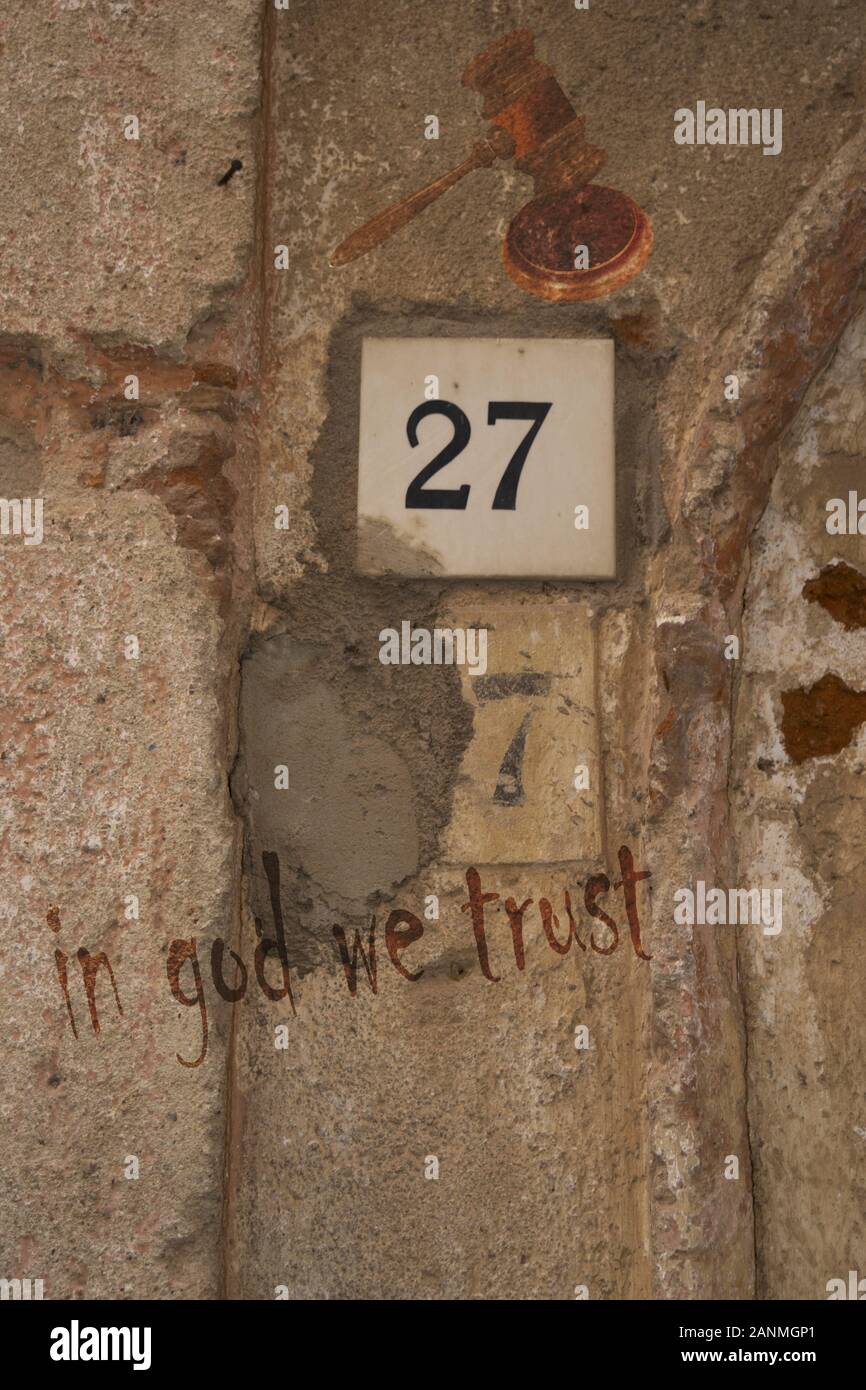 Auf Gott vertrauen wir auf einer alten Mauer geschrieben Stockfoto