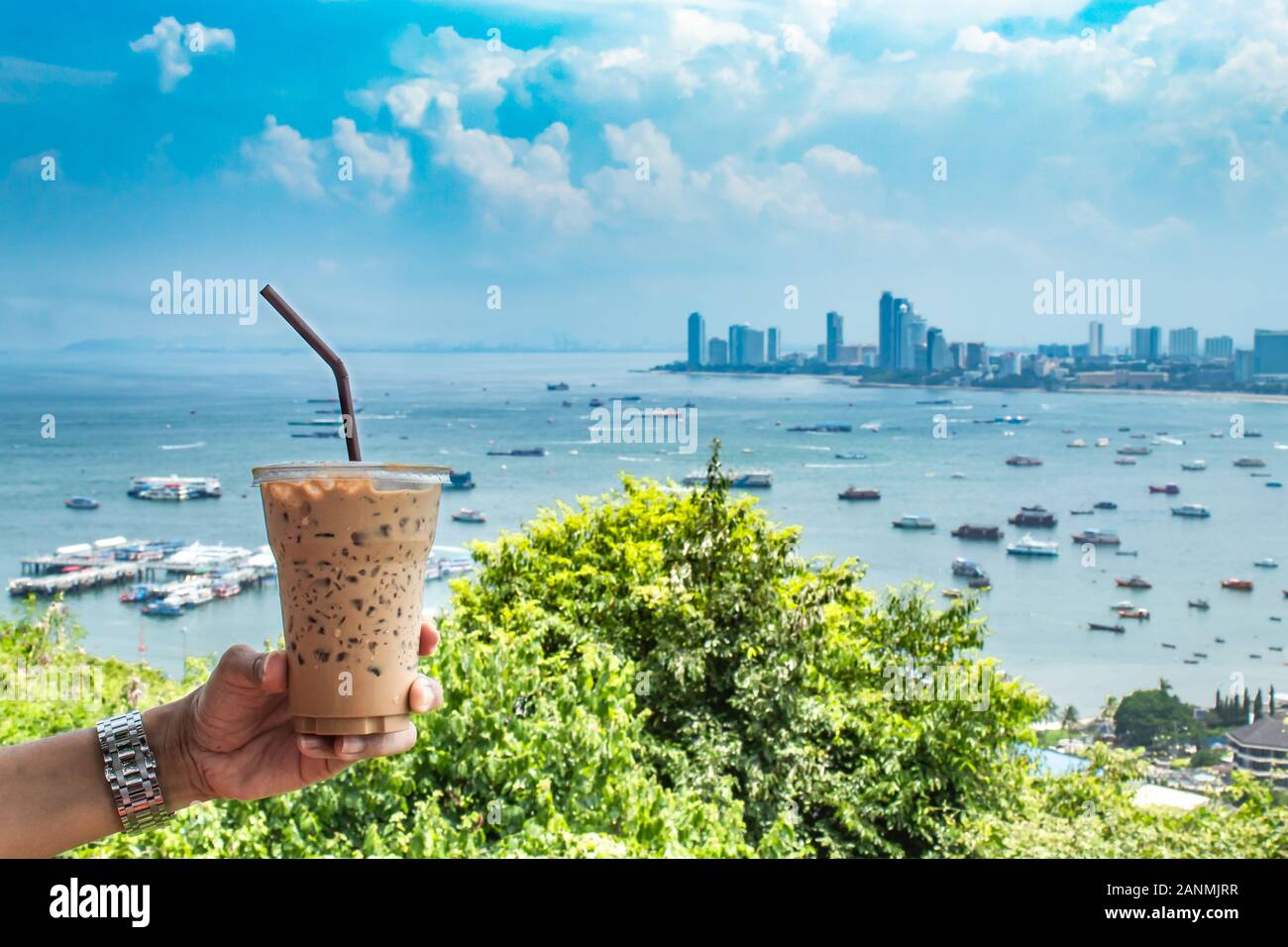 Hand, Eiskaffee und Meer mit viele Boote an der Pattaya in Thailand. Stockfoto
