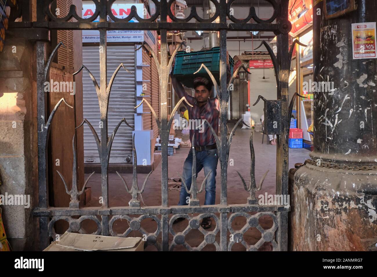 Ein Portier steht hinter einem schmiedeeisernen Zaun auf dem Crawford-Markt (Mahatma Jyotiba Phule Market), einem Obstmarkt der Kolonialzeit in Mumbai, Indien Stockfoto