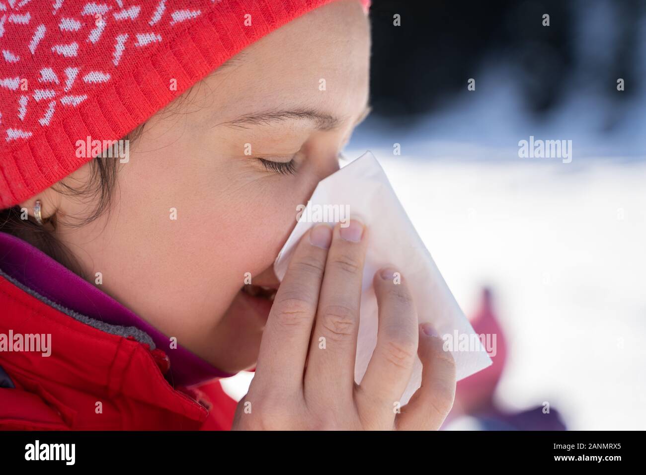 Hübsche junge Frau bläst Ihre Nase mit einem Taschentuch Outdoor im Winter Stockfoto