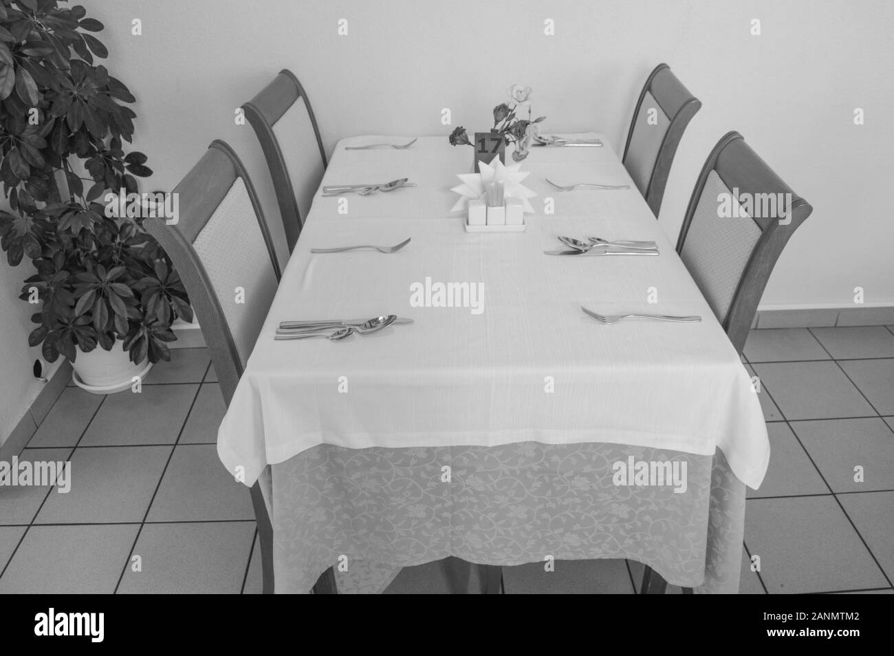Festliche Tisch mit Tischdecke und Besteck im Restaurant warten auf Gäste, Seitenansicht, schwarzen und weißen Rahmen. Stockfoto