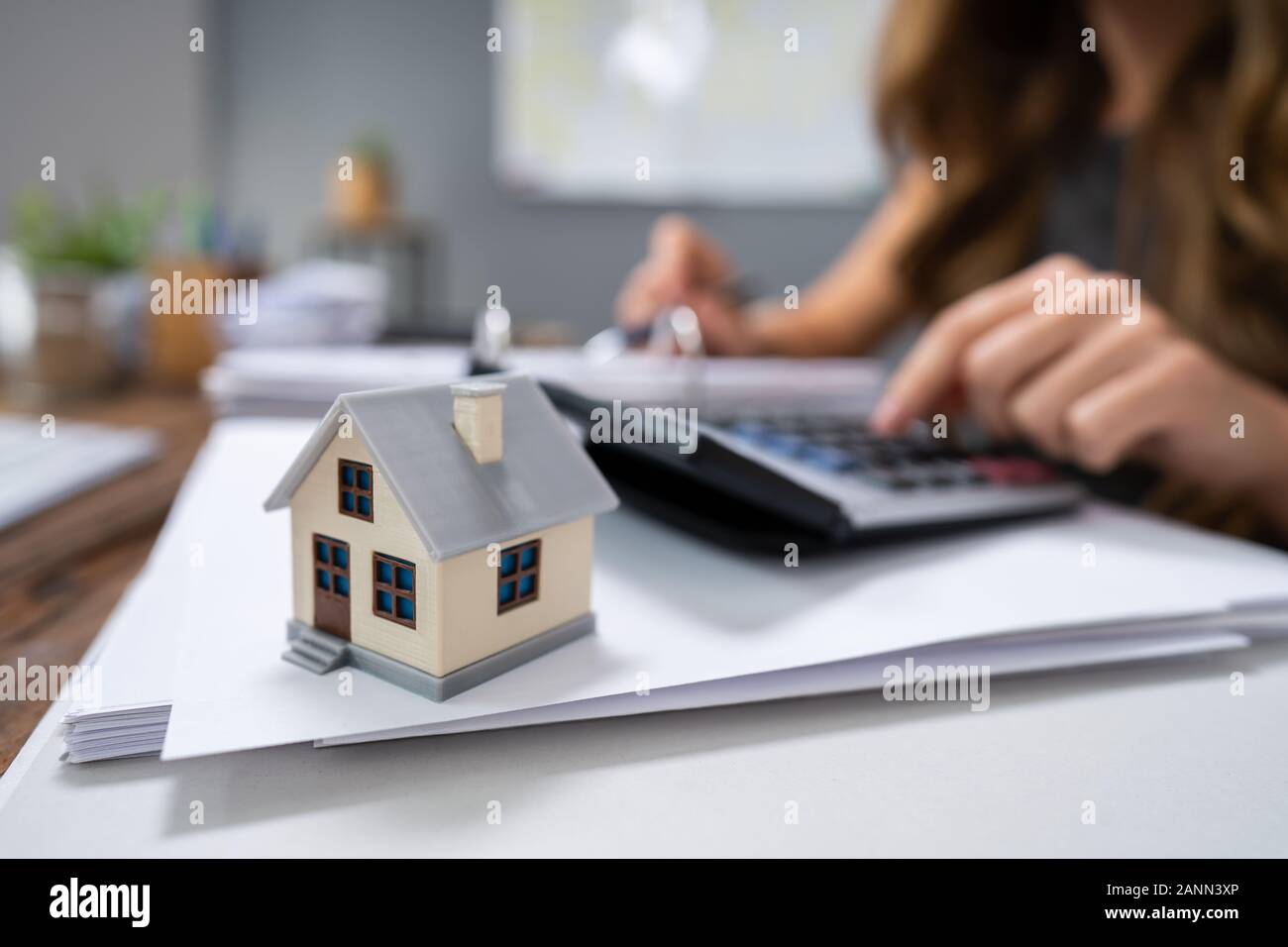 Nahaufnahme einer Person Hand Berechnung Immobilien Steuer auf hölzernen Schreibtisch Stockfoto
