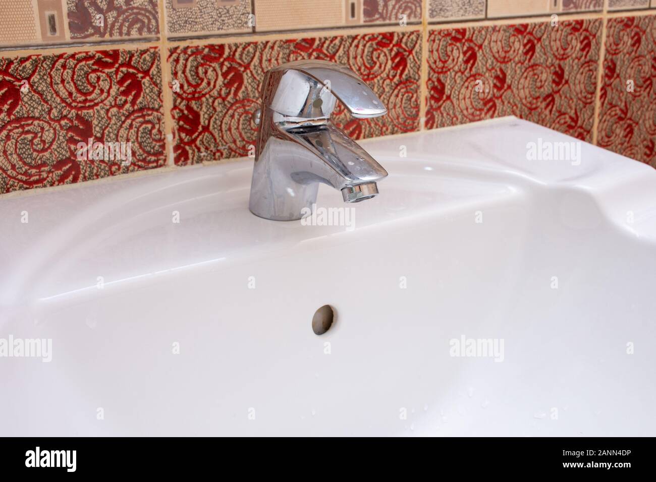 Glänzend Wohn- Silber bad Armatur oder auf einem weißen Keramik Waschbecken tippen. Sanitär, DIY, oder Wartungskonzepte. Stockfoto