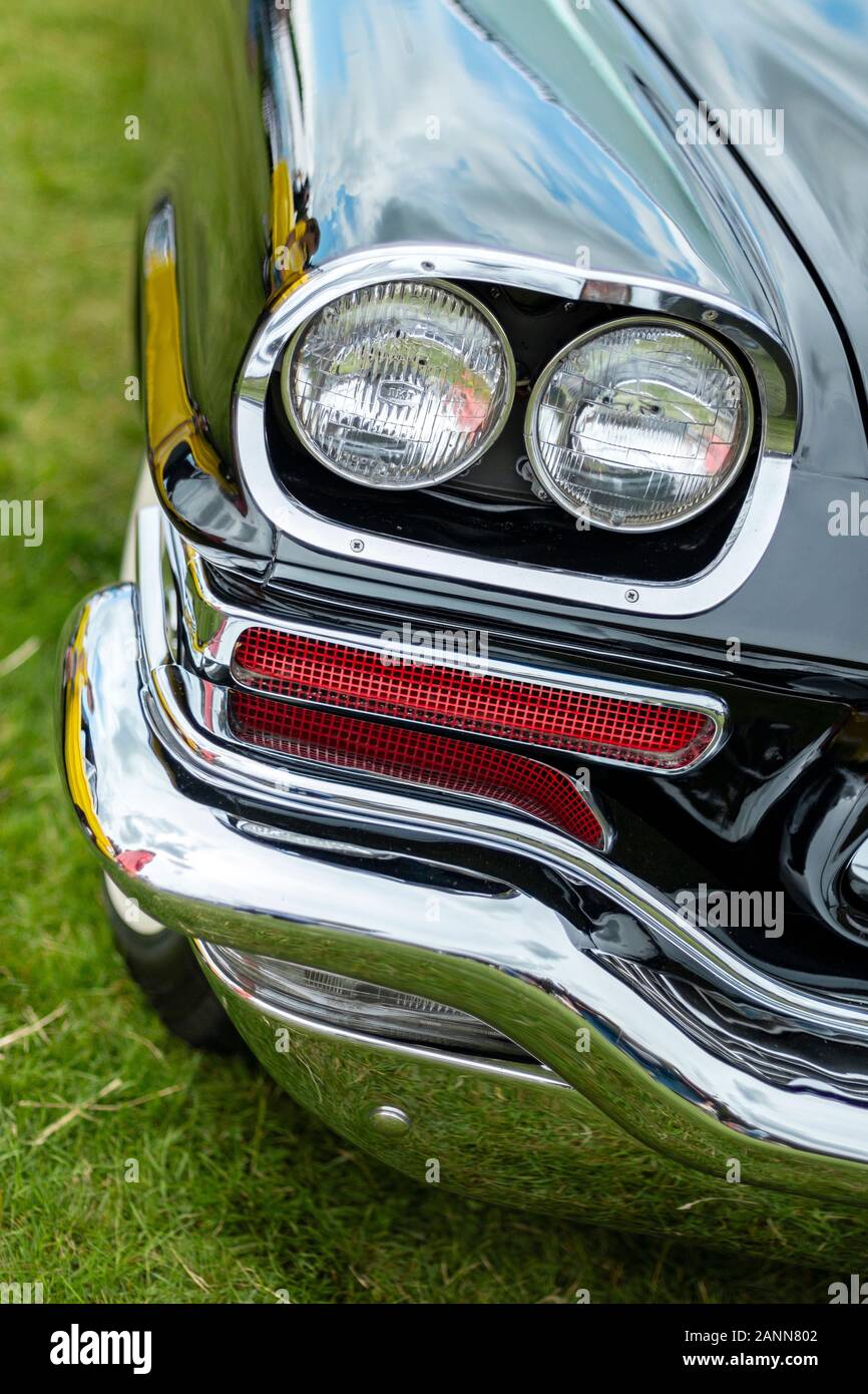 Nahaufnahme eines klassischen chrysler 300-Fahrzeugs aus den 1950er Jahren mit glänzendem Chrom-Stoßfänger und Scheinwerferdetails vor einem grasbewachsenen Hintergrund Stockfoto