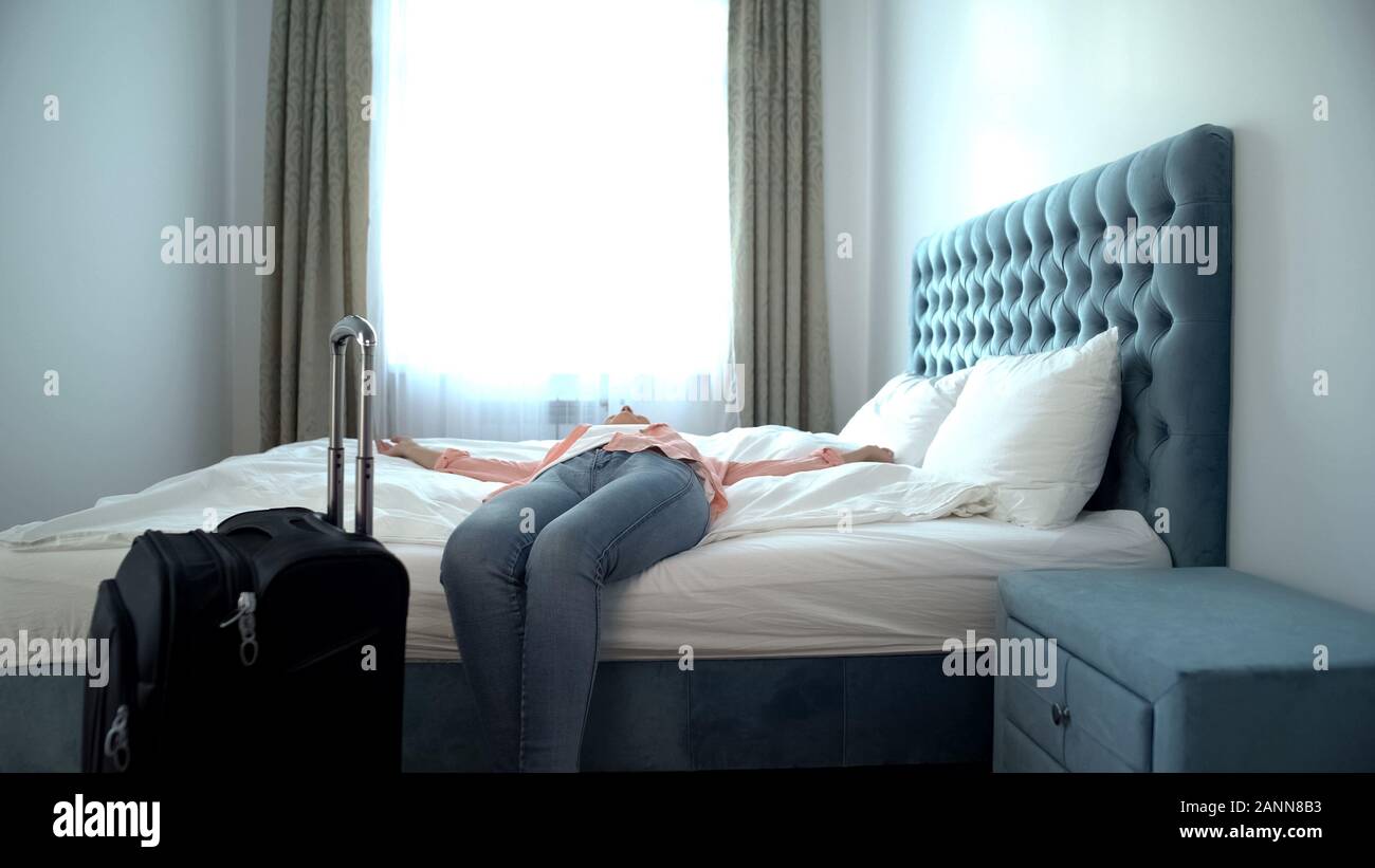 Entspannt Frau mit Koffer liegen auf großen bequemen Bett im Hotel Zimmer Ferienhäuser Stockfoto