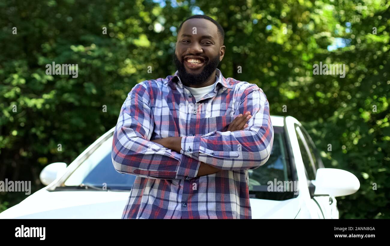 Happy afro-amerikanischer Mann lächelnd auf Cam, lehnte sich neuen Automobil, Rent Service Stockfoto