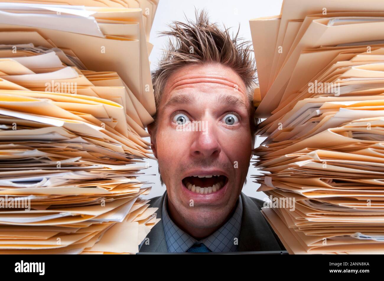 Büroangestellter Hilfeschreie aus zwischen zwei riesigen Stapel von Aktenordnern betonte Stockfoto