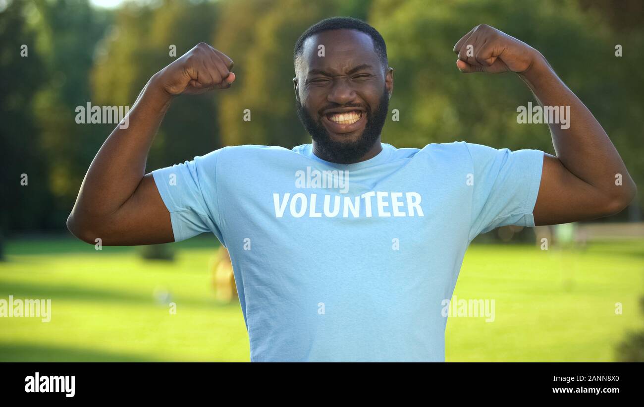 Afrikanische männlichen Freiwilligen-T-Shirt zeigt Stärke Geste, spende Einheit aufgeregt Stockfoto