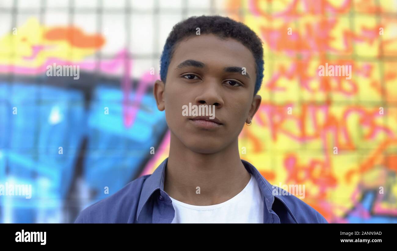 Cool männliche Teenager mit gefärbten Haaren auf der Suche Kamera auf Graffiti Wand Hintergrund Stockfoto