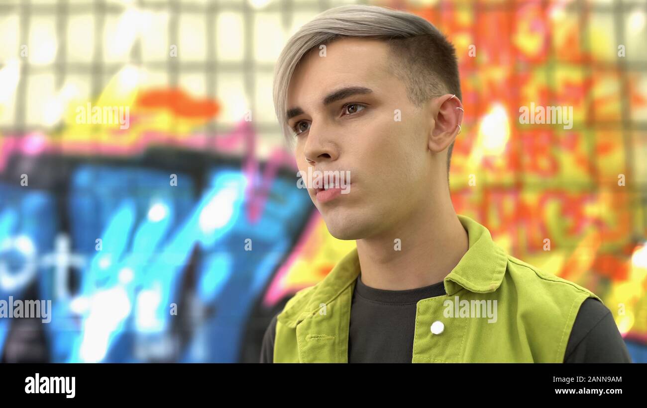 Männliche Teenager mit gefärbten Haaren auf Graffiti Gebäude Hintergrund posiert, Mode Stockfoto