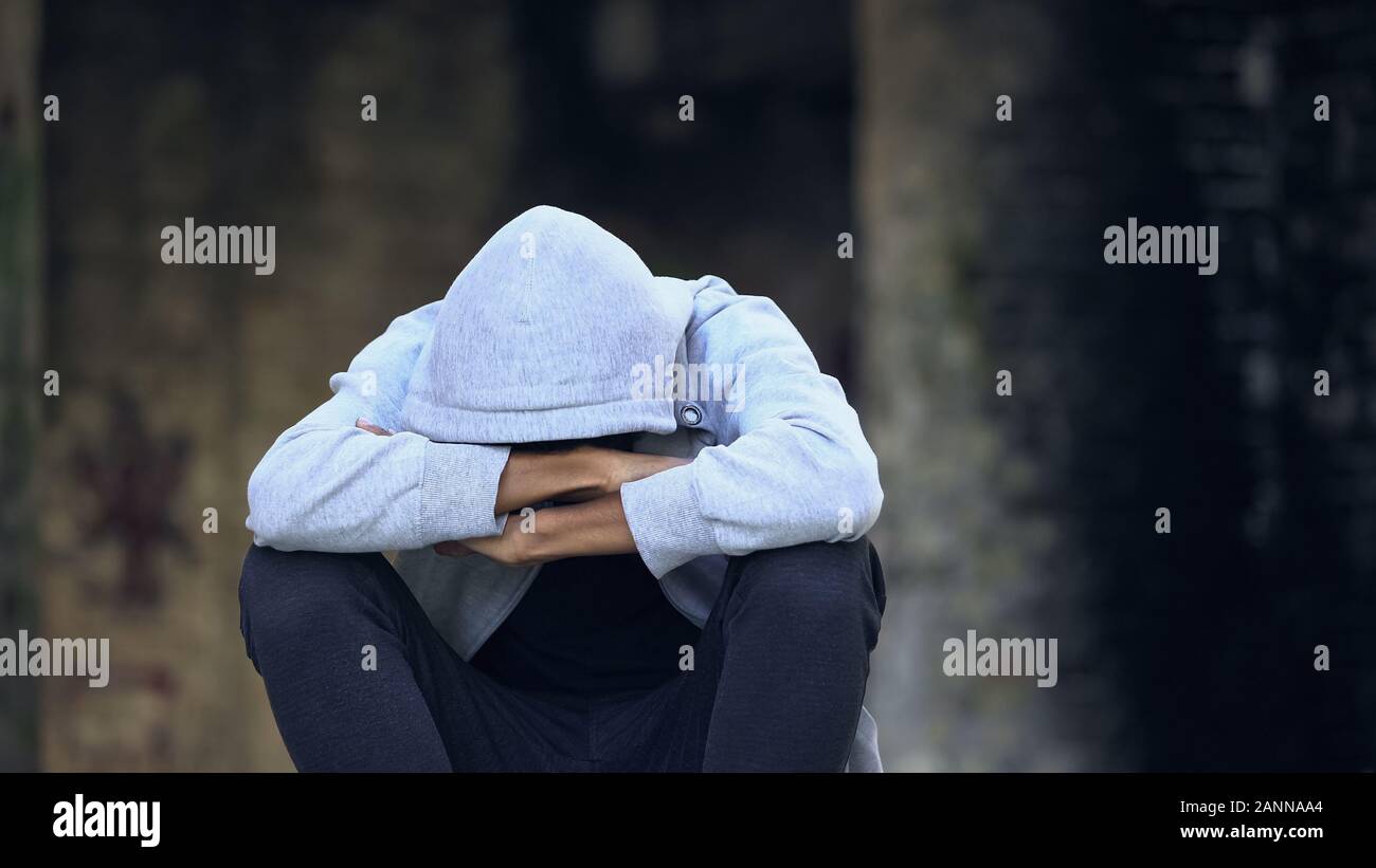 Traurig afro-amerikanischer Jugendlicher in der Motorhaube sitzen Straße allein, das Denken von Problemen Stockfoto