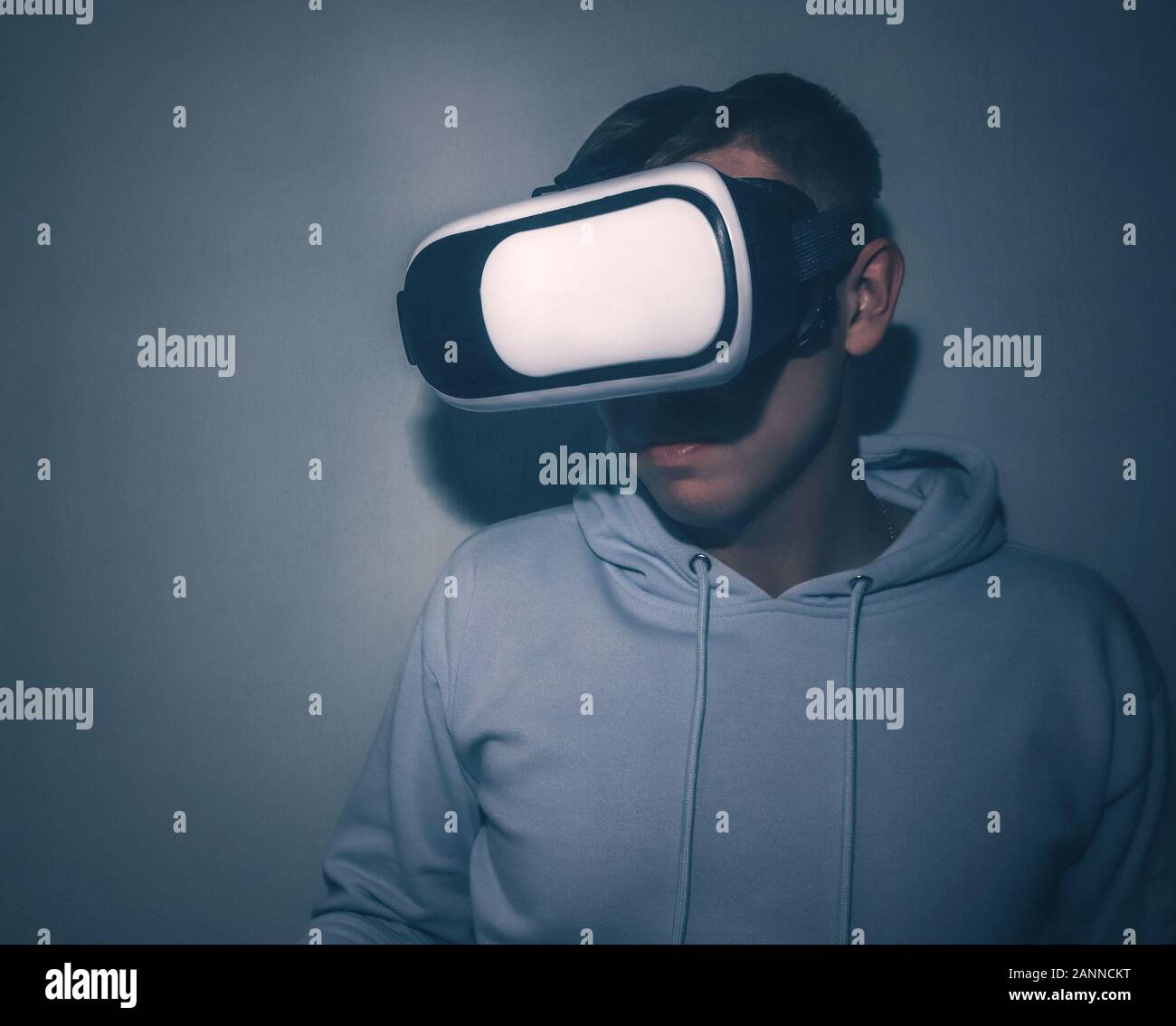 Ein junger Mann schaut in virtual reality Brillen close-up auf dem blauen Hintergrund. Stockfoto