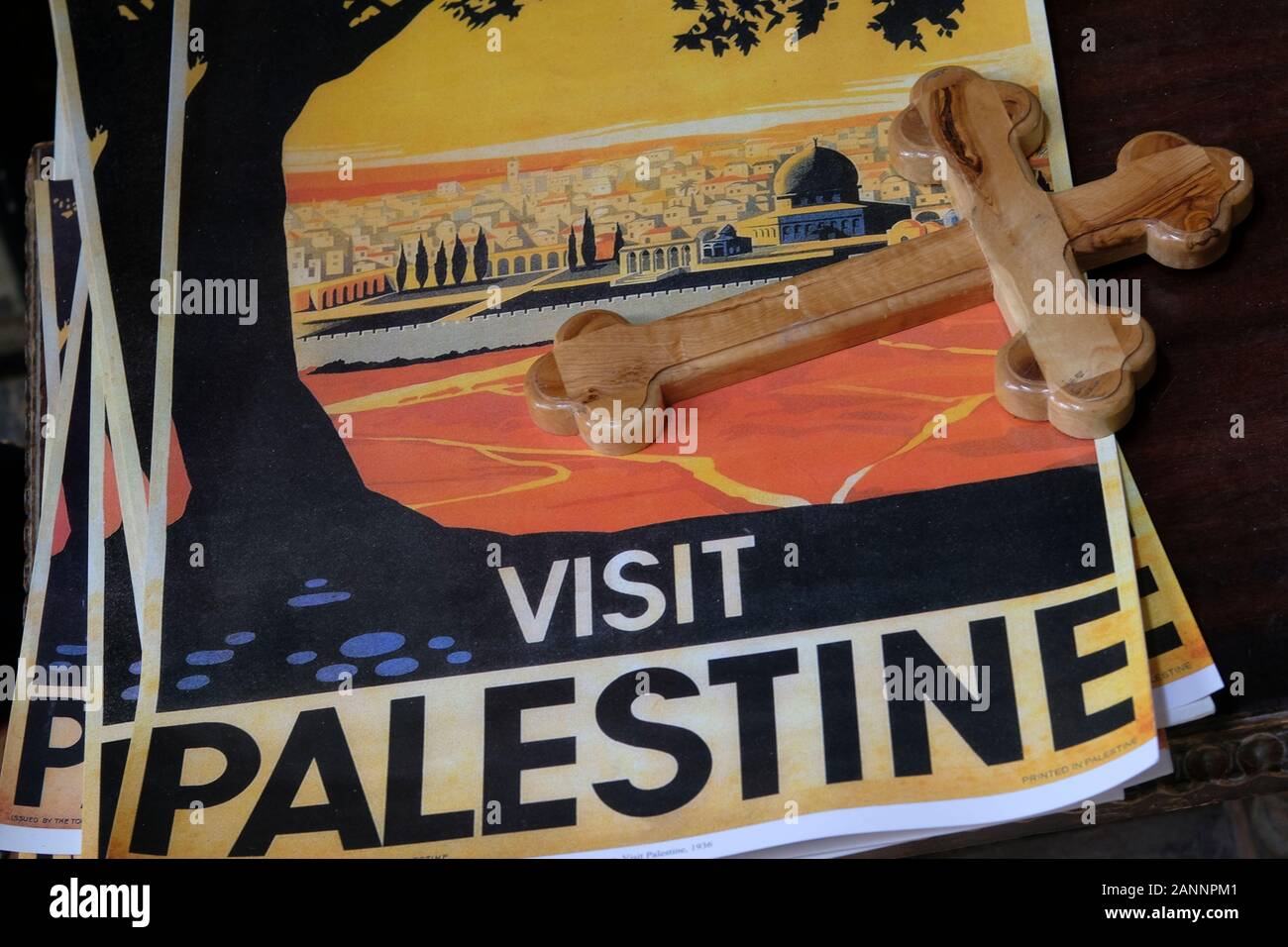 Ein hölzernes Kreuz legt über Plakate von Besuchen Palästina reisen Poster in einem souvenirshop an der alten Stadt Jerusalem Israel. Original Plakat 1936 entworfen wurde von Franz Krausz Anreise und Einreise nach Israel zu fördern, das Plakat Wunde bis zu einem Symbol des palästinensischen Nationalismus. Stockfoto