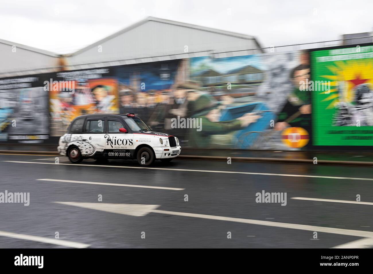 Auto vorbei politische Graffiti an der Wand in West Belfast, Belfast, Nordirland Stockfoto