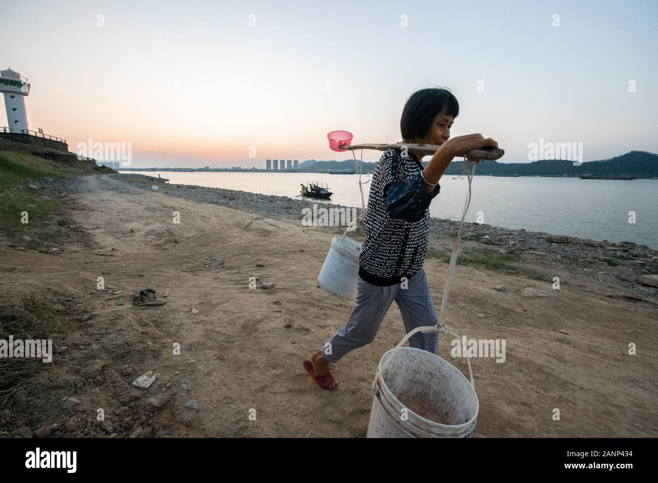 Eine Frau mit zwei großen Eimer Wasser auf ihre Schulter, abgerufen aus dem Xi Fluss, Zhaoqing, Guangdong, in China Stockfoto