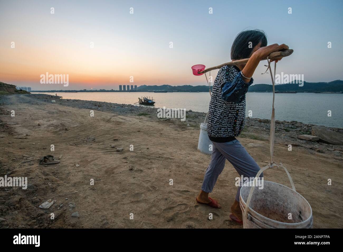 Eine Frau mit zwei großen Eimer Wasser auf ihre Schulter, abgerufen aus dem Xi Fluss, Zhaoqing, Guangdong, in China Stockfoto