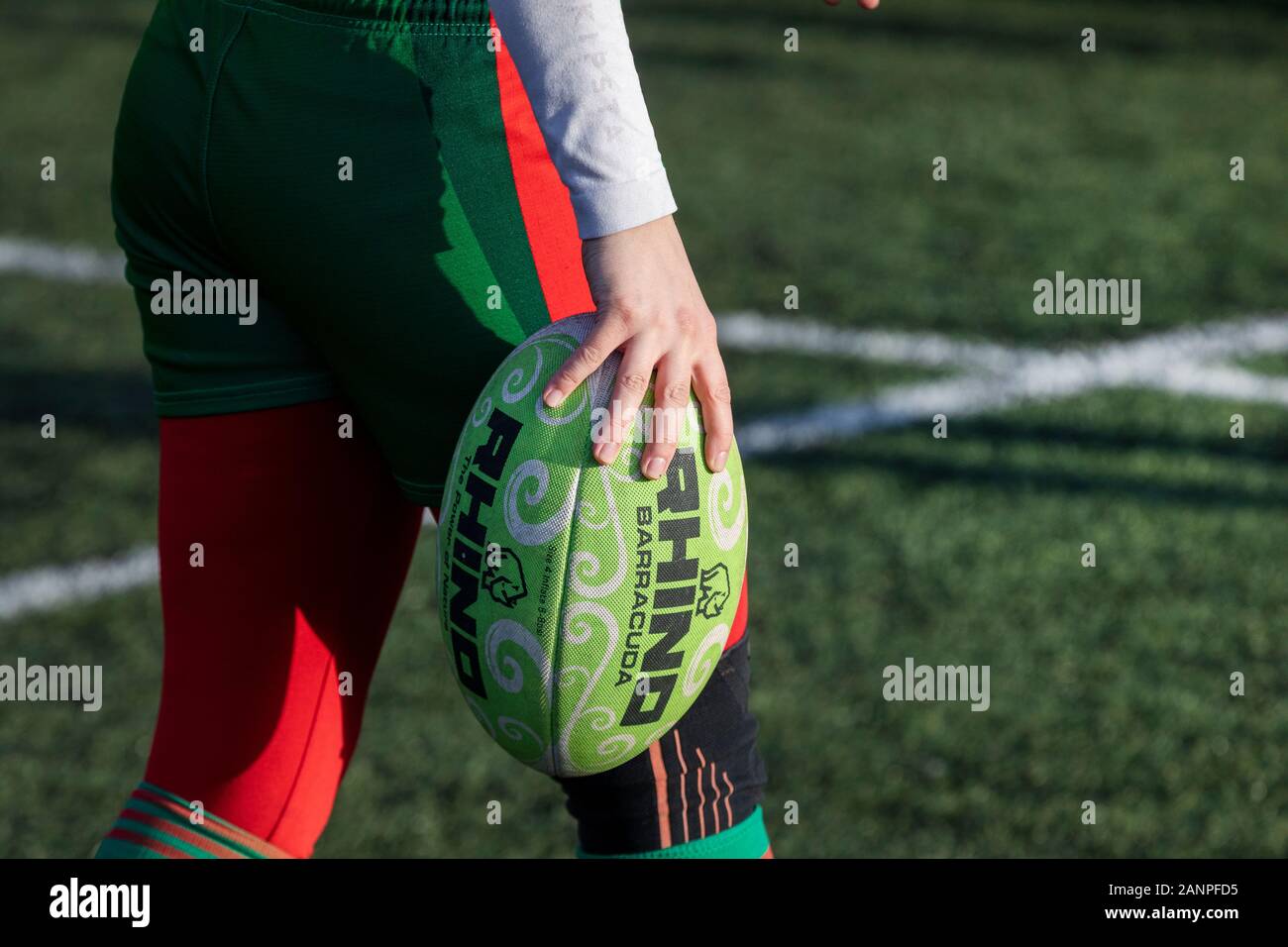 Ein weiblicher Rugbyspieler trägt einen Ball in ihren Händen auf einem Feld eines Stadions Stockfoto