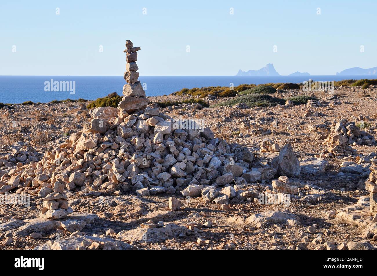 Gestapelte Steine Stapel in Cap de Barbaria mit Es Vedrá Inselchen im fernen Ende (Formentera, Pityusic Inseln, Balearen, Mittelmeer, Spanien) Stockfoto