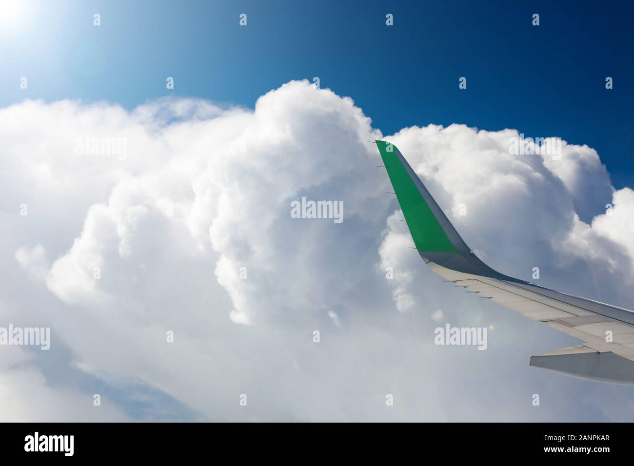 Blick aus dem Fenster eines Flugzeuges, weiße Wolken, blauer Himmel, Flügel eines Flugzeugs. Ray in der linken oberen Ecke. Stockfoto