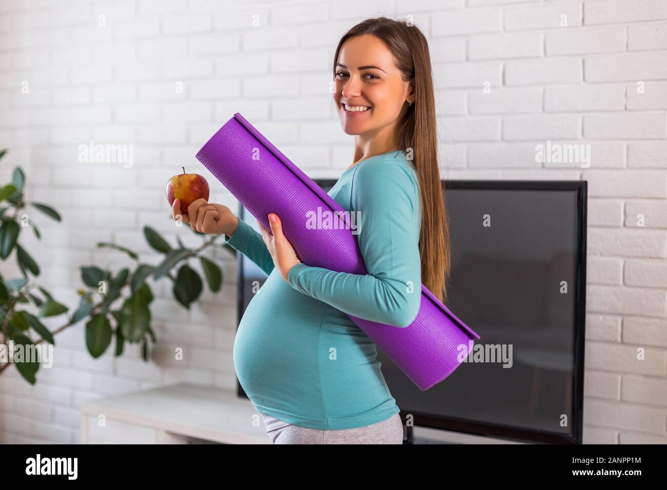 Schöne Frau, die zeigen, dass Sie gesund essen und trainieren, während sie schwanger ist. Stockfoto