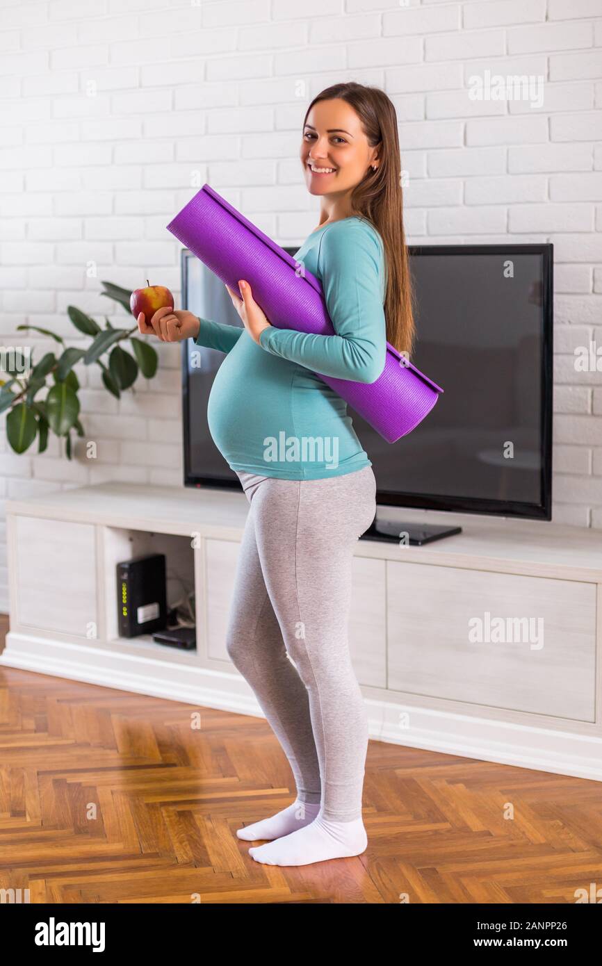 Schöne Frau, die zeigen, dass Sie gesund essen und trainieren, während sie schwanger ist. Stockfoto