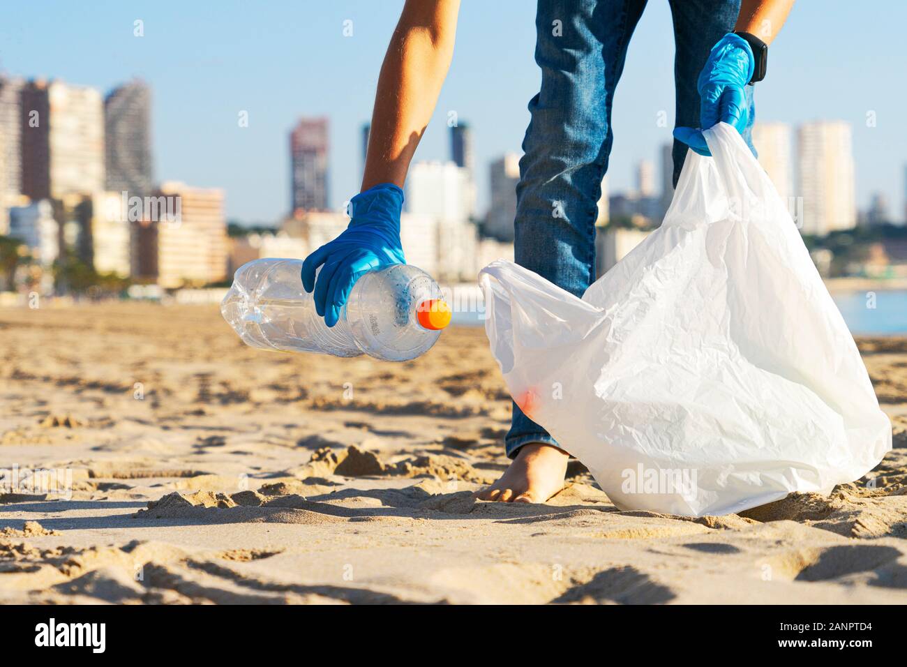 Sauberer Strand aus Kunststoff. Hand herauf Plastikflasche Papierkorb vom Strand und in Plastikbeutel für Recycling Stockfoto