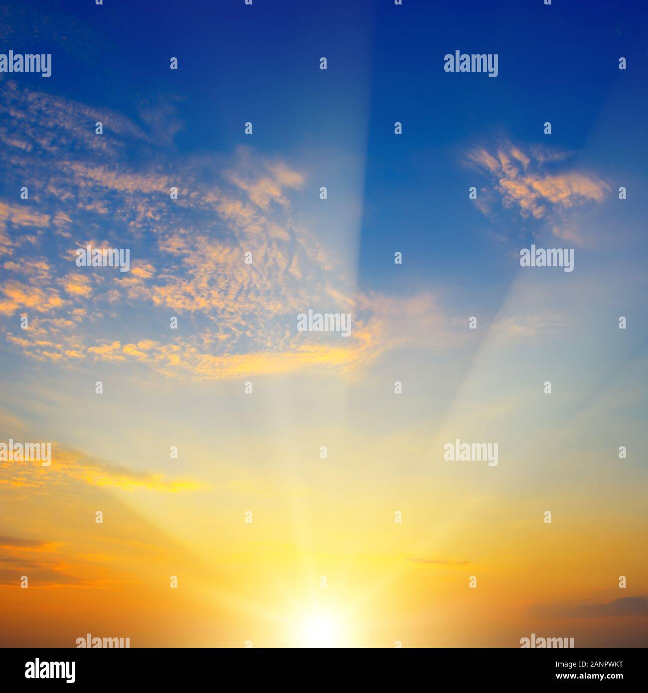 Einen malerischen Sonnenuntergang mit Sonnenstrahlen gegen strahlend blauen Himmel und Wolken Stockfoto