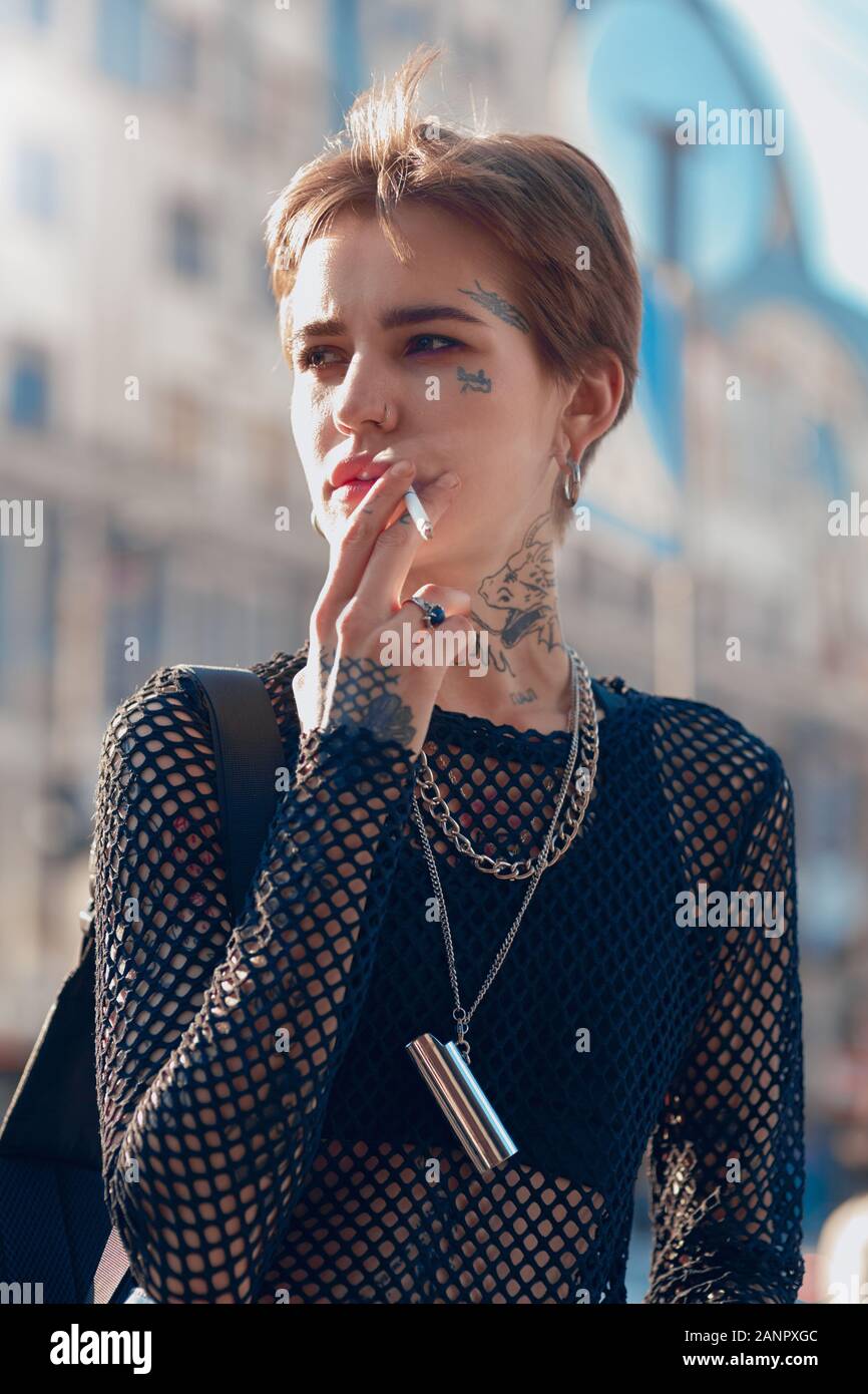 Urban Style. Junge stilvolle Frau, die Hand in der Tasche im Freien rauchen Zigarette beiseite schauen neugierig close-up Stockfoto