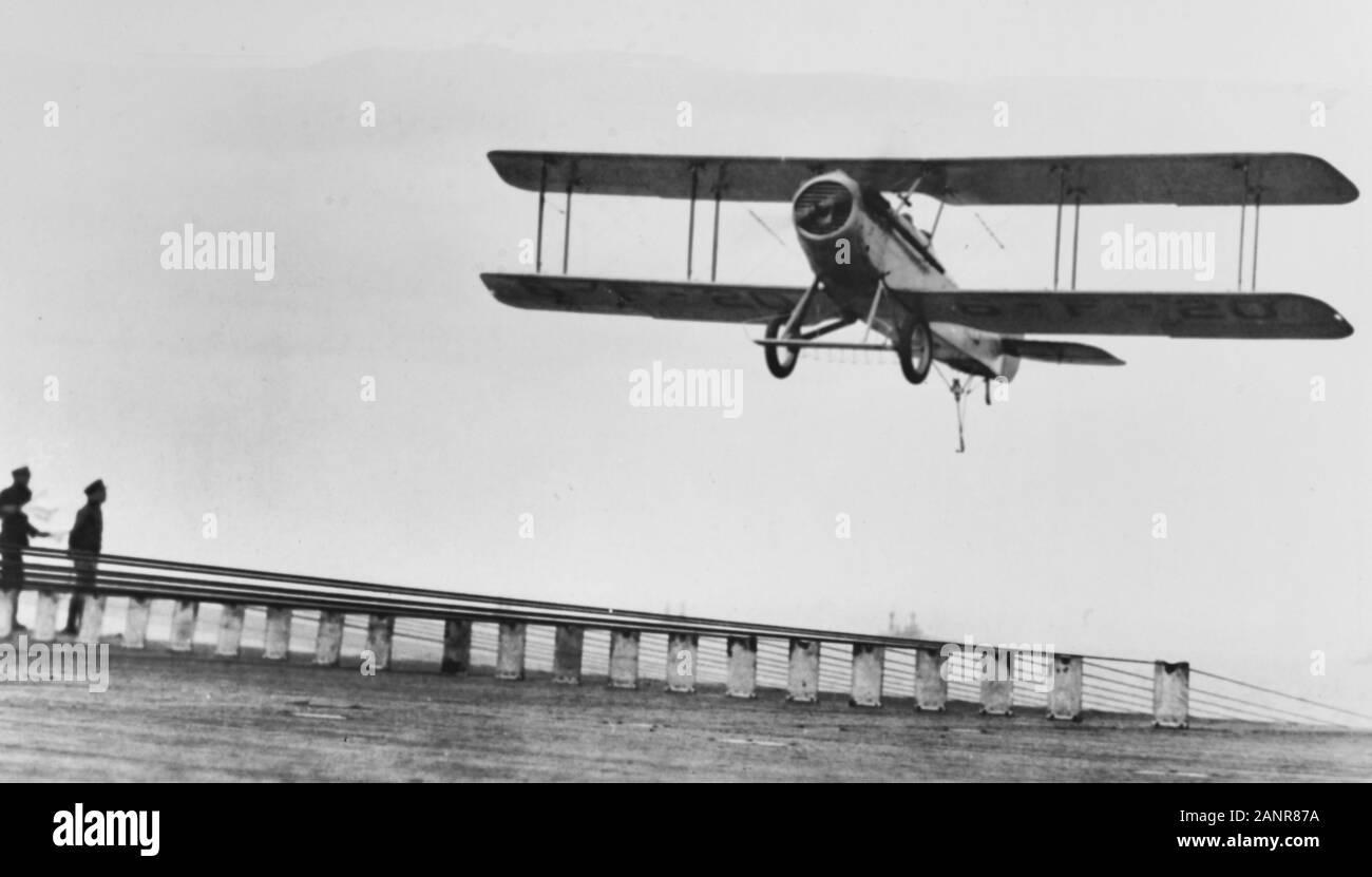 VOUGHT VE-7s VE-7s der Kämpfe Squadron 6 (VF-6), Landung an Bord der USS LANGLEY (CV-1) ca. 1927. Unter Flügel Kennzeichnung "6-F-16' zeigt diese Ebene wird als ein Dienstprogramm Flugzeug über seine Kämpfer Kraft zu VF-6 angebracht. Träger Decks hatten die übliche Seitliche verhaften Drähte, sondern auch die Anordnung der vorderen und hinteren Drähten wie hier gesehen. Diese Drähte propped Up auf hölzernen "fiddle Blocks', das kleine Ankerförmigen gefangen werden die Haken an der Unterseite des Hauptfahrwerks Achse das Flugzeug von Schlenker von der Flight Deck zu beiden Seiten, wenn sein Schwanz haken die Verhaftung gefangen zu halten. Stockfoto