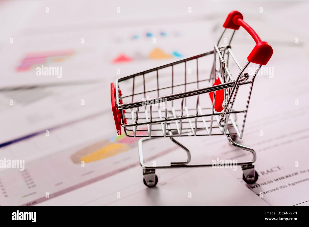 Leer Warenkorb auf Dokumente mit Grafiken und wirtschaftlichen Daten, defokussiertem Hintergrund. Stockfoto