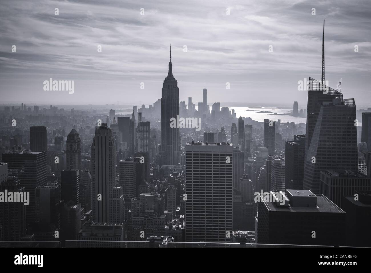Blick auf Manhattan New York City aus einer Höhe. 2-in-1-Silhouetten der Wolkenkratzer, der Fluss schimmert in den Strahlen der untergehenden Sonne. Getonten Bild eines Stockfoto