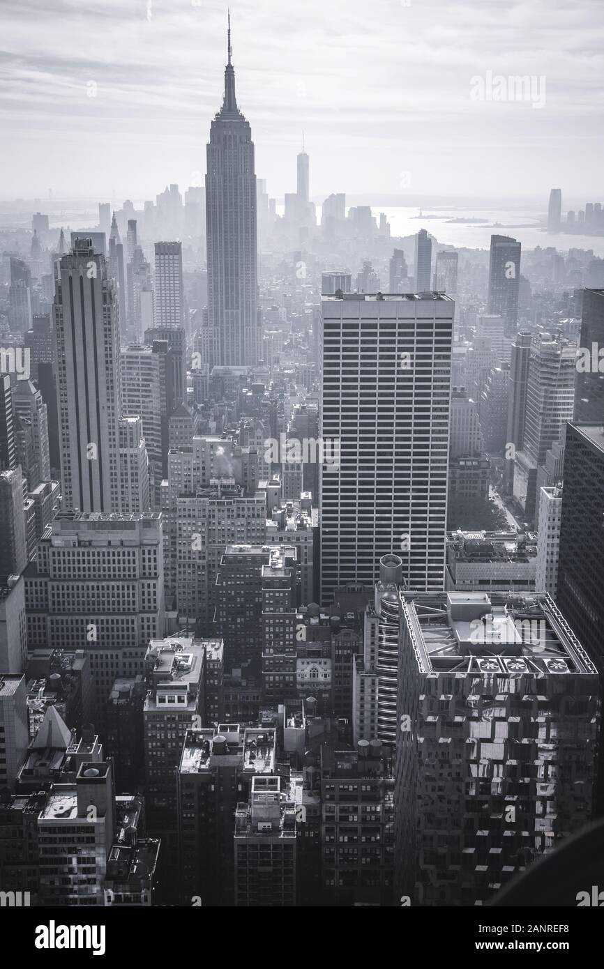 Blick auf Manhattan New York City aus einer Höhe. 2-in-1-Silhouetten der Wolkenkratzer, der Fluss schimmert in den Strahlen der untergehenden Sonne. Getonten Bild eines Stockfoto