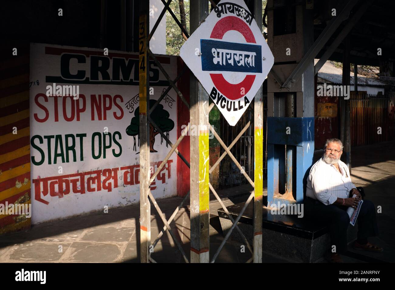 Ein Pendler, der auf dem Bahnsteig des Bahnhofs Byculla in Mumbai, Indien, sitzt und auf seinen Zug in die Vororte wartet Stockfoto