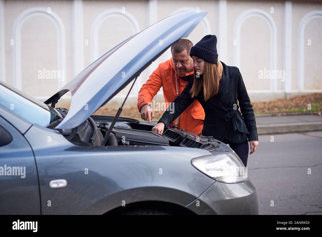 Junges Paar in der Nähe ein Auto mit offener Haube auf der Straße. Stockfoto