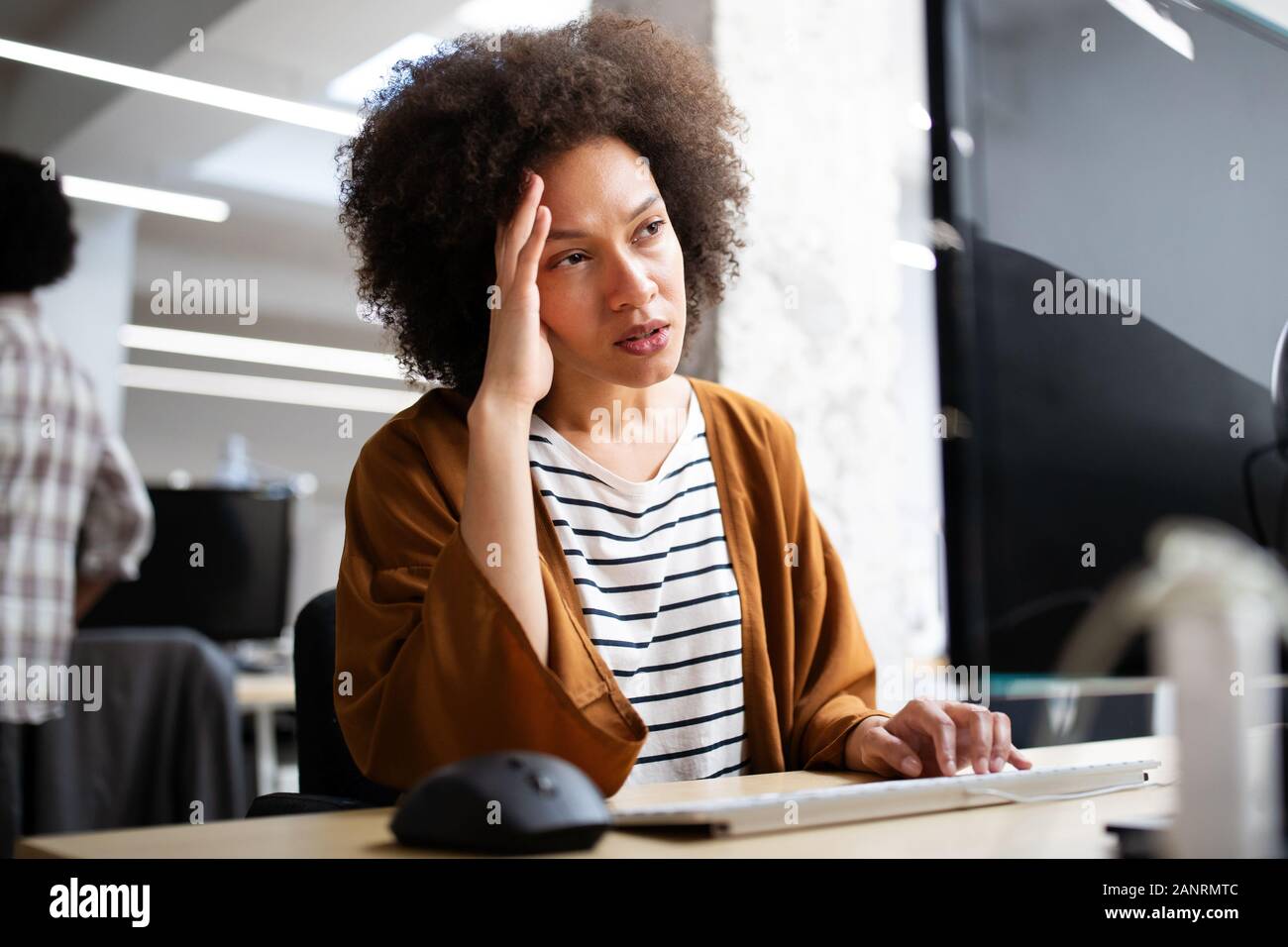 Überarbeitet und frustrierte junge Frau vor der Computer im Büro Stockfoto