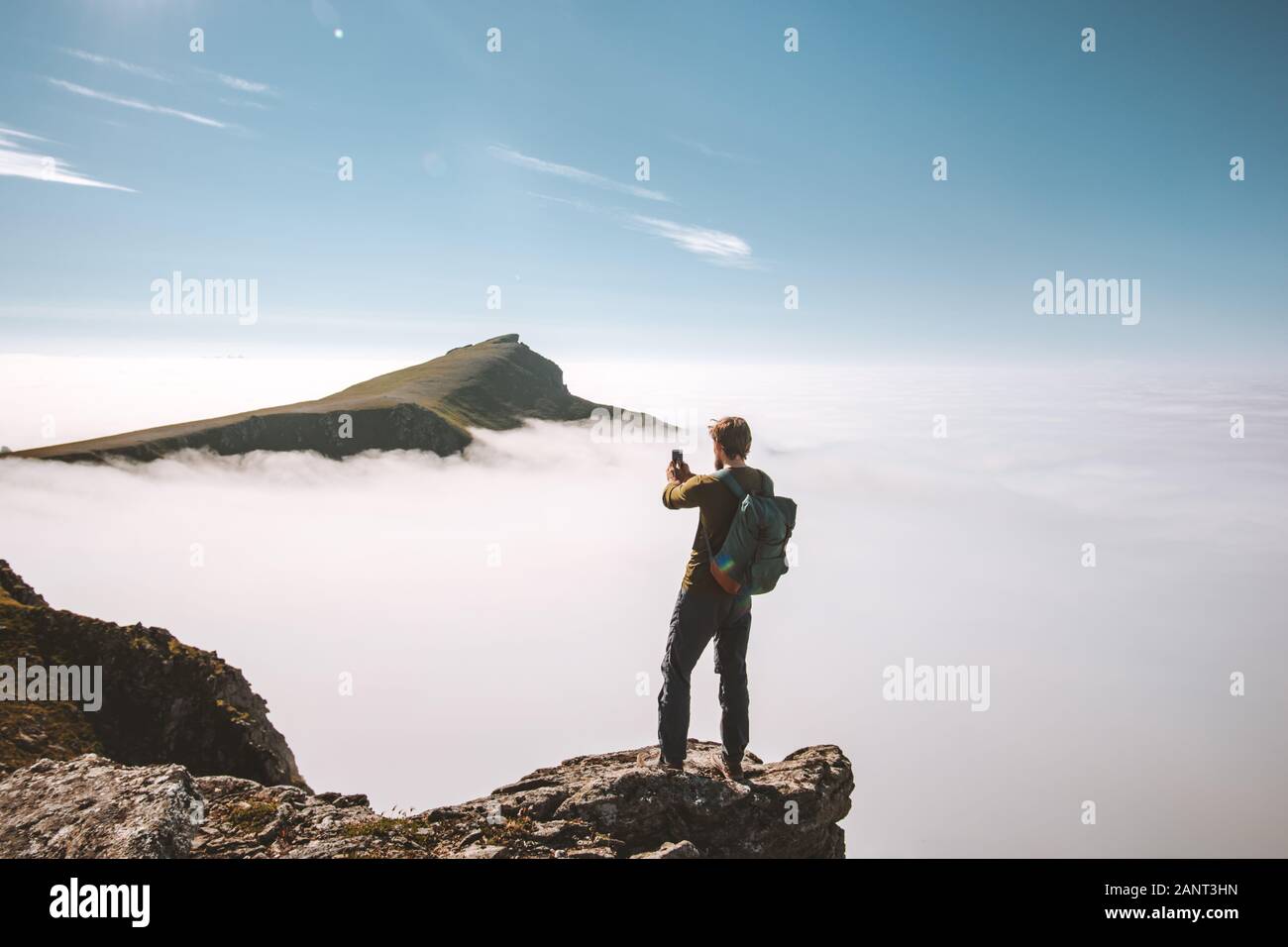 Man Blogger mit Smartphone auf Klippe reisen Ferien Abenteuer Content Creator Einflussnehmer lifestyle Outdoor über Wolken Landschaft in Norwegen Stockfoto